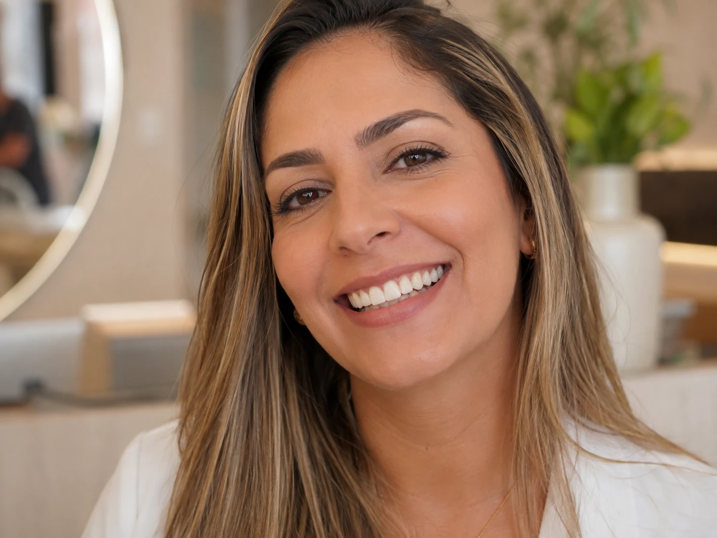 Paciente sorrindo na recepção da clínica após tratamento com facetas de porcelana