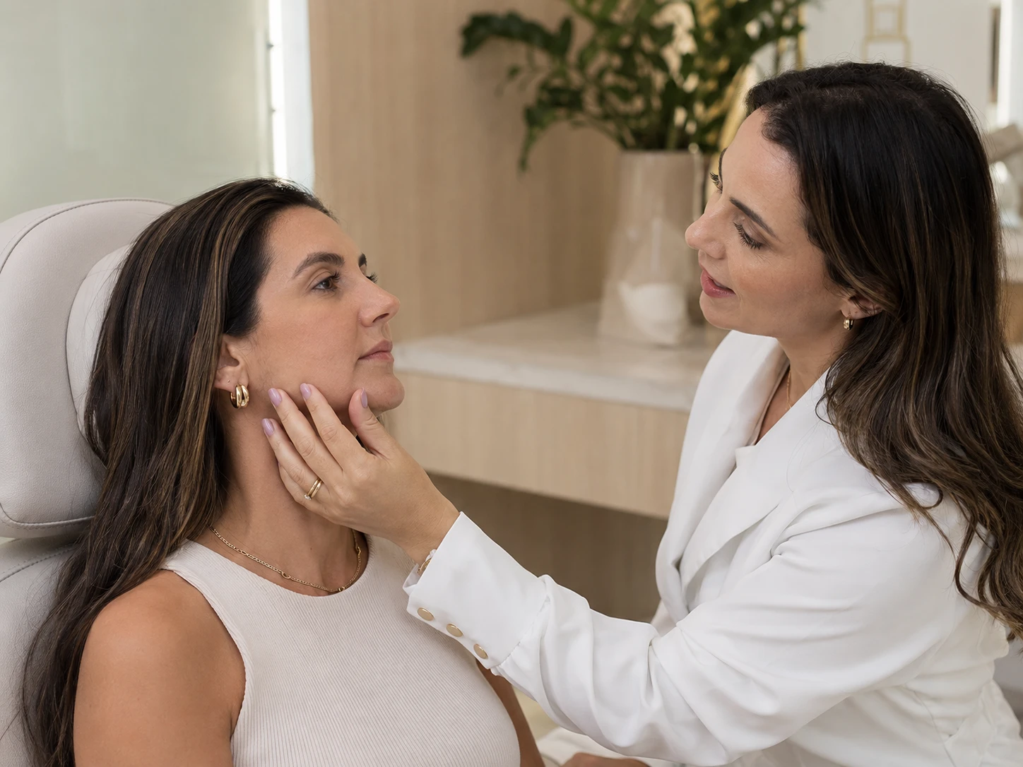 Dentista avaliando o contorno facial de uma paciente antes de um procedimento de harmonização orofacial